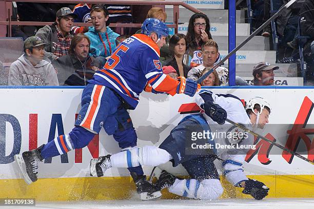 Ben Eager of the Edmonton Oilers shoves Adam Pardy of the Winnipeg Jets off his feet during a preseason NHL game at Rexall Place on September 23,...