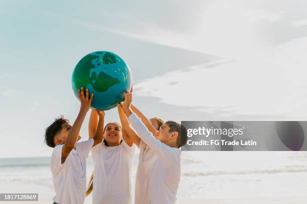 crianças segurando um planeta na praia - happy earth day - fotografias e filmes do acervo