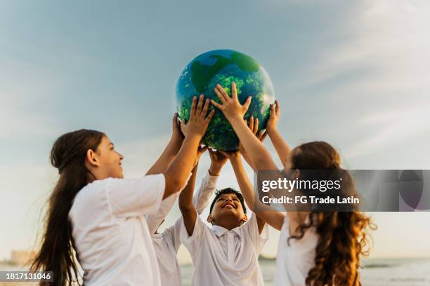 children holding a planet on the beach - preservação ambiental imagens e fotografias de stock