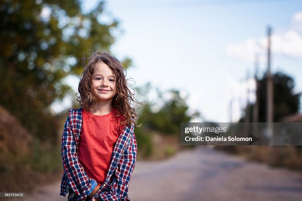 Smiling boy with long hair on the country road