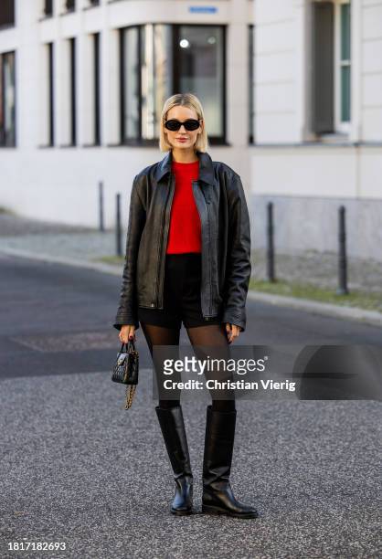 Mandy Bork wears black COS leather jacket, red COS jumper, Zara shorts, Chanel boots & bag, Celine sunglasses on November 27, 2023 in Berlin, Germany.