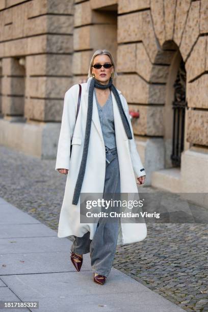 Tina Haase wears Birgitte Herskind white wool coat, H&M grey baggy jeans, Sézane burgundy Box bag, Burgundy heels, grey wool scarf on November 27,...