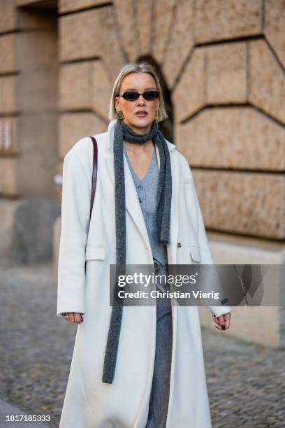 Tina Haase wears Birgitte Herskind white wool coat, H&M grey baggy jeans, Sézane burgundy Box bag, Burgundy heels, grey wool scarf on November 27,...