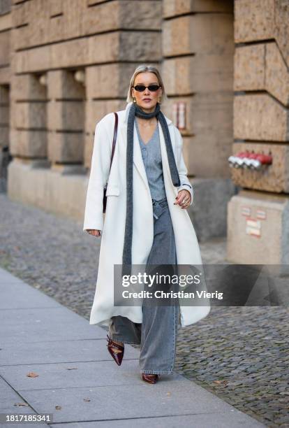 Tina Haase wears Birgitte Herskind white wool coat, H&M grey baggy jeans, Sézane burgundy Box bag, Burgundy heels, grey wool scarf on November 27,...