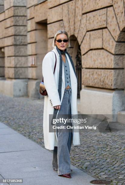 Tina Haase wears Birgitte Herskind white wool coat, H&M grey baggy jeans, Sézane burgundy Box bag, Burgundy heels, grey wool scarf on November 27,...