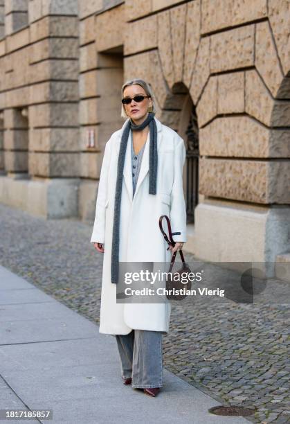 Tina Haase wears Birgitte Herskind white wool coat, H&M grey baggy jeans, Sézane burgundy Box bag, Burgundy heels, grey wool scarf on November 27,...