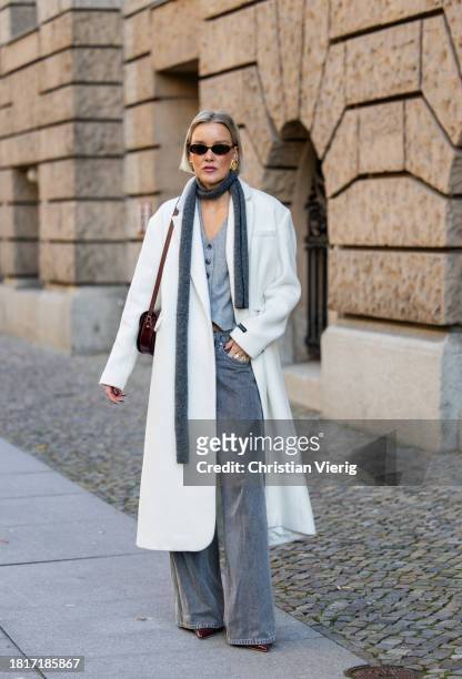 Tina Haase wears Birgitte Herskind white wool coat, H&M grey baggy jeans, Sézane burgundy Box bag, Burgundy heels, grey wool scarf on November 27,...