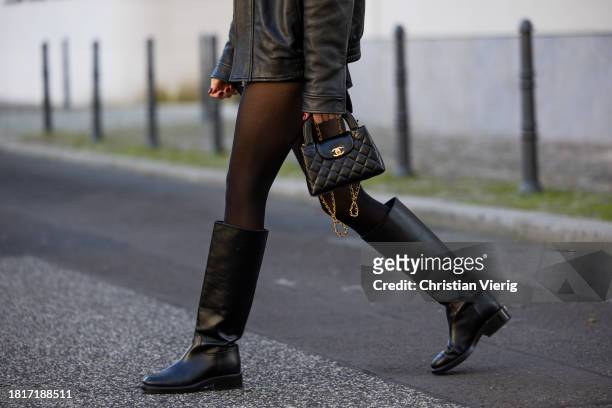 Mandy Bork wears black COS leather jacket, red COS jumper, Zara shorts, Chanel boots & bag, Celine sunglasses on November 27, 2023 in Berlin, Germany.