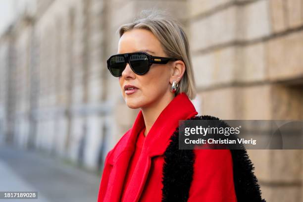 Tina Haase wears red Sézane sweater, red h&m oversize coat, YPS Black leather pants, Gucci aviator sunglasses, Proenza Schouler Black Teddy bag,...