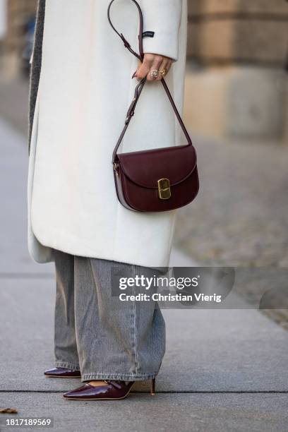 Tina Haase wears Birgitte Herskind white wool coat, H&M grey baggy jeans, Sézane burgundy Box bag, Burgundy heels, grey wool scarf on November 27,...