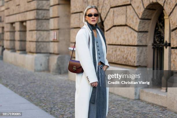 Tina Haase wears Birgitte Herskind white wool coat, H&M grey baggy jeans, Sézane burgundy Box bag, Burgundy heels, grey wool scarf on November 27,...