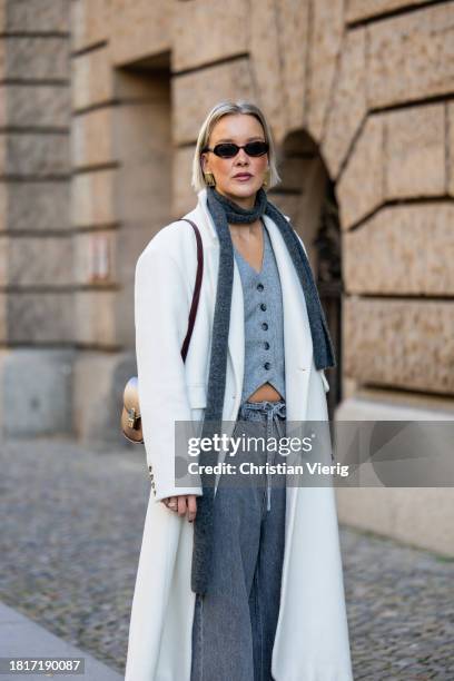 Tina Haase wears Birgitte Herskind white wool coat, H&M grey baggy jeans, Sézane burgundy Box bag, Burgundy heels, grey wool scarf on November 27,...