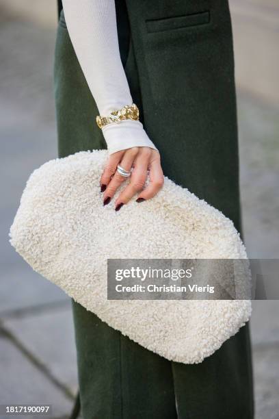 Tina Haase wears Karpova green wool pants & apron dress, white COS Teddy Clutch bag, white turtleneck, Zara heeled boots on November 27, 2023 in...