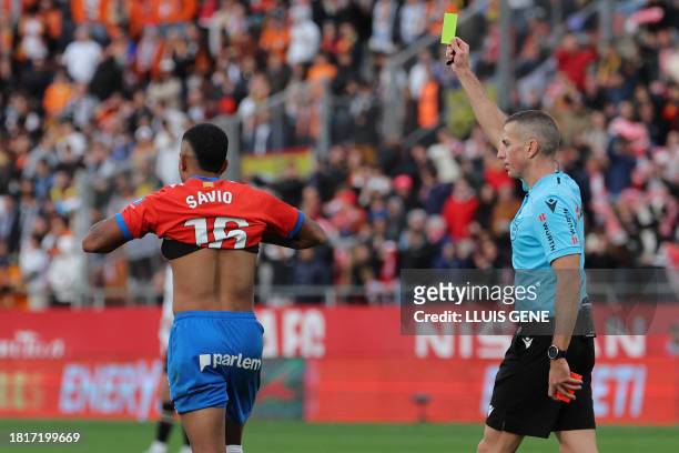 Spanish referee Iglesias Villanueva presents a yellow card to Girona's Brazilian forward Savio Moreira for taking his jersey out during the...