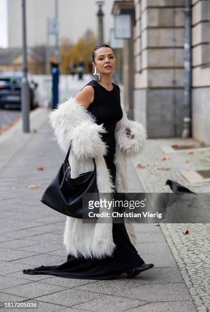 Amelie Stanescu wears long mermaid evening dress by Weekday, faux fur long coat by Weekday, big oversized leather bag by Smaak Amsterdam, y project...