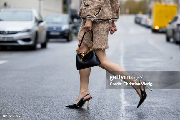 Lea Naumann wears beige teddy set Etro, black bag Etro, heels H&M, earrings Mango on November 27, 2023 in Berlin, Germany.