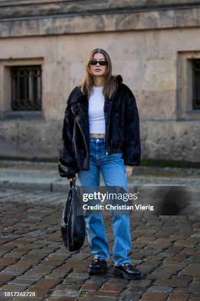 Sophia Geiss wears black fake fur jacket, white shirt, denim jeans, Bottega Veneta bag on November 27, 2023 in Berlin, Germany.