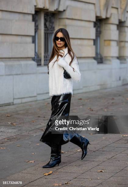 Jill Asemota wears white pullover Parfois, black vinyl SkirtH&M Studio, boots: Massimo Dutti, sunglasses Loewe, bag Vintage on November 27, 2023 in...