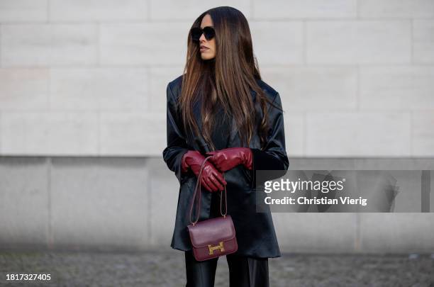 Jill Asemota wears black blazer Dodo Bar Or, T-Shirt The Attico, flared pants Maison Margiela, sunglasses Loewe, red burgundy bag Hermes, gloves on...