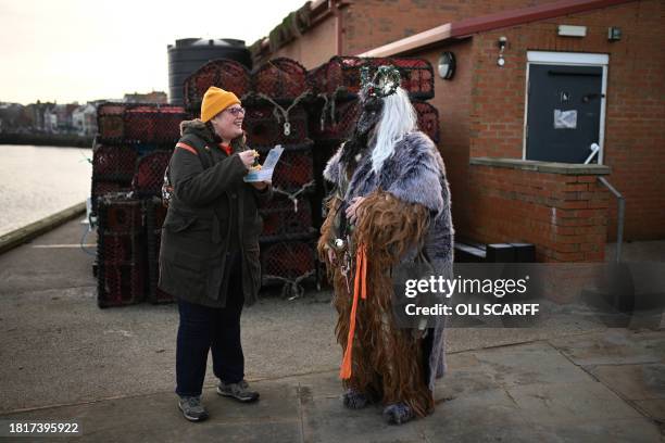 Participant dressed as "Krampus", a half-goat, half-demon figure that punishes people who misbehave during the Christmas season, chats to a member of...