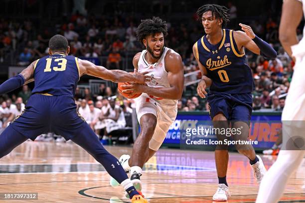 Miami forward Norchad Omier drives to the basket while defended by Notre Dame forward Carey Booth and forward Tae Davis in the first half as the...