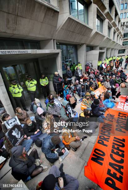 Supporters of Just Stop Oil sit on the floor outside The Ministry of Justice, behind a banner saying 'No Prison For Peaceful Protest' on December 2,...