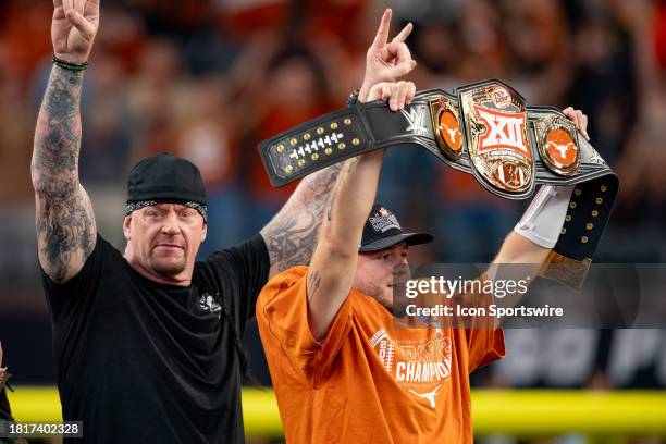 Texas Longhorns quarterback Quinn Ewers holds up the WWE Big 12 Championship belt as WWE legend The Undertaker throws horns up after winning the Big...