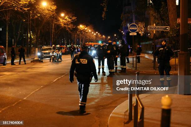 Police officers stand guard in a security perimetre set after one person was killed and two others wounded in a knife attack in Paris, on December 2,...