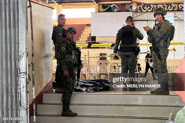 Military personnel stand guard at the entrance of a gymnasium while police investigators look for evidence after a bomb attack at Mindanao State...