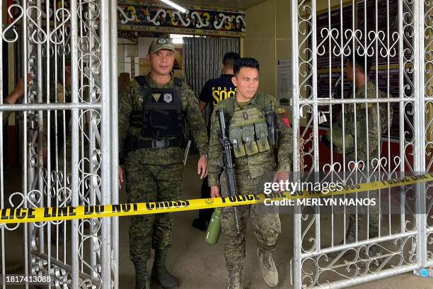 Military personnel stand guard at the entrance of a gymnasium while police investigators look for evidence after a bomb attack at Mindanao State...