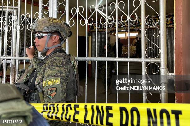 Military personnel stand guard at the entrance of a gymnasium while police investigators look for evidence after a bomb attack at Mindanao State...