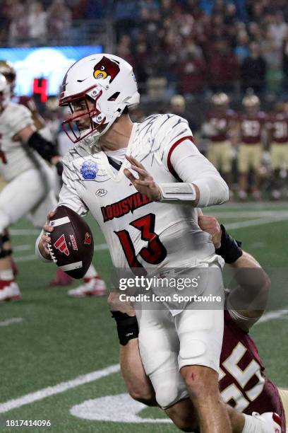 Louisville Cardinals quarterback Jack Plummer is dragged down from behind for a sack by Florida State Seminoles defensive lineman Braden Fiske during...