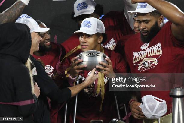 Florida State Seminoles quarterback Jordan Travis a day after having surgery holds the football trophy with his teammates during the ACC Football...