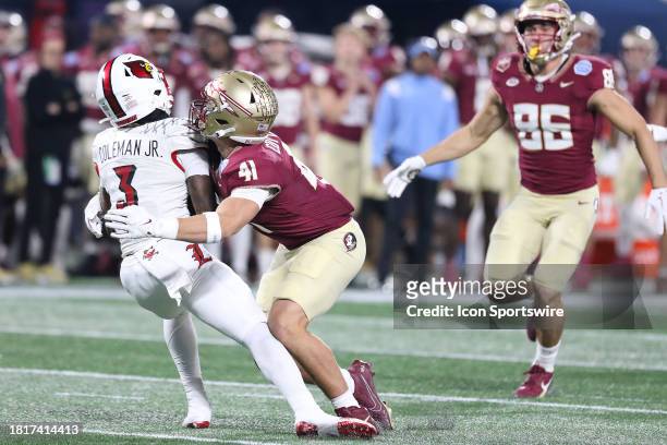 Louisville Cardinals wide receiver Kevin Coleman looks to return a punt, but Florida State Seminoles linebacker AJ Cottrill tackles Colman just after...