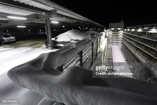 December 2023, Bavaria, Munich: The top floor of a parking garage at Munich Airport is partially covered in snow. Munich Airport resumed flight...