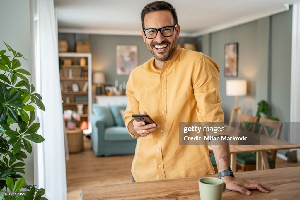 Portrait d’homme joyeux utilisant un smartphone à la maison