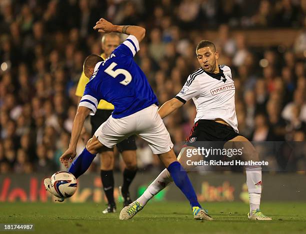 John Heitinga of Everton is tripped by Adel Taarabt of Fulham during the Captial One Cup Third Round match between Fulham and Everton at Craven...