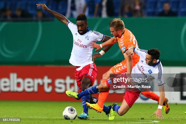 Johan Djourou and Hakan Calhanoglu of Hamburg and Florian Trinks of Greuther Fuerth battle for the ball during the DFB Cup second round match between...