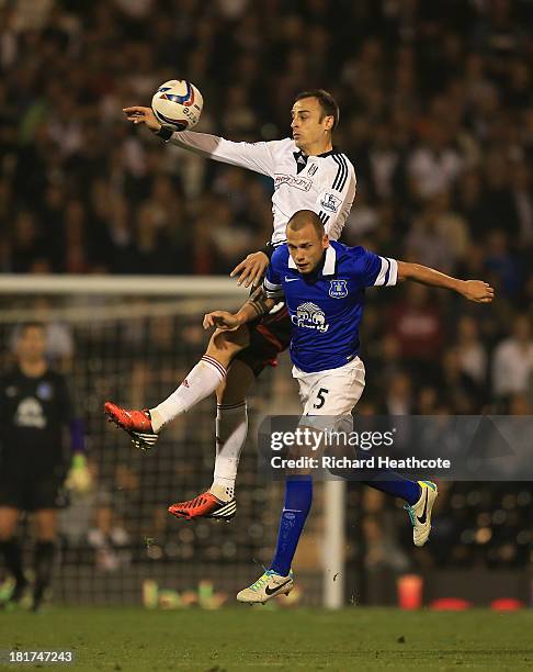 Dimitar Berbatov of Fulham jumps with John Heitinga of Everton during the Captial One Cup Third Round match between Fulham and Everton at Craven...