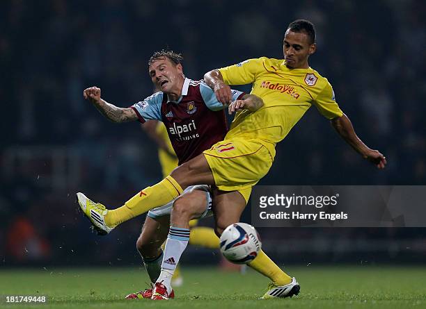 Matt Taylor of West Ham is tackled by Peter Odemwingie of Cardiff City during the Capital One Cup third round match between West Ham United and...