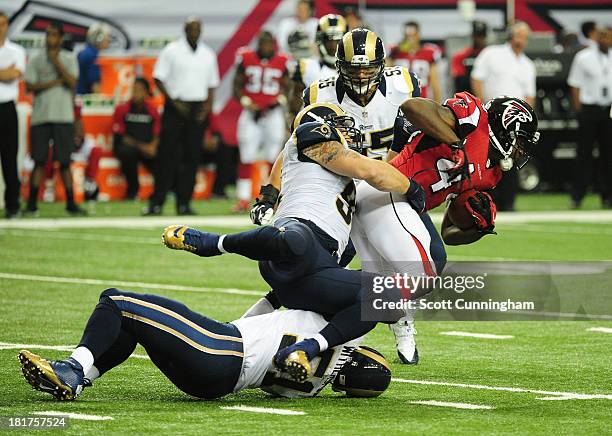 Jason Snelling of the Atlanta Falcons is tackled by Chris Long of the St. Louis Rams at the Georgia Dome on September 15, 2013 in Atlanta, Georgia.