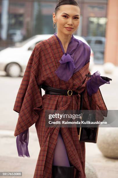 Guest wears purple tights, a brown long coat, and black long leather boots during the Tashkent Fashion Week 2023 on November 27, 2023 in Tashkent,...