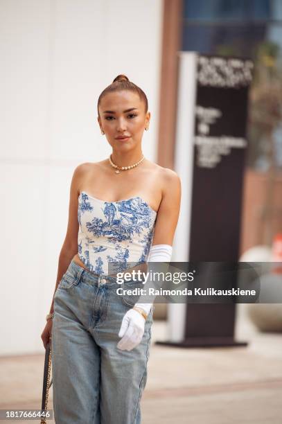 Guest wears blue jeans, one long white glove, and a blue and white corset during the Tashkent Fashion Week 2023 on November 27, 2023 in Tashkent,...
