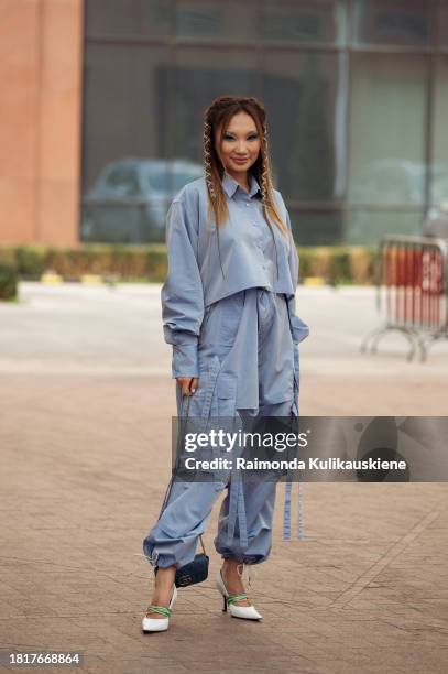 Guest wears blue cargo pants and a matching cropped top, white shoes with colorful decorations, and a blue mini bag during the Tashkent Fashion Week...