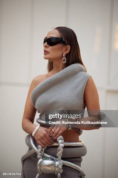 Guest wears a grey mini skirt, matching top black and white boots with a platform, silver bag, and sunglasses during the Tashkent Fashion Week 2023...