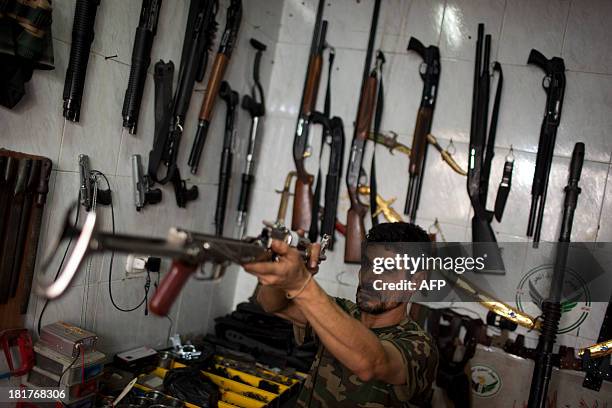 Abu Mohammad checks an AK47 at his gun shop in the Fardos district of Syria's northern city of Aleppo on September 21, 2013. While most Syrians get...
