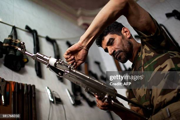 Abu Mohammad checks an AK47 at his gun shop in the Fardos district of Syria's northern city of Aleppo on September 21, 2013. While most Syrians get...