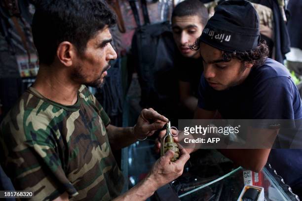 Abu Mohammad shows a grenade to a client at his gun shop in the Fardos district of Syria's northern city of Aleppo on September 21, 2013. While most...