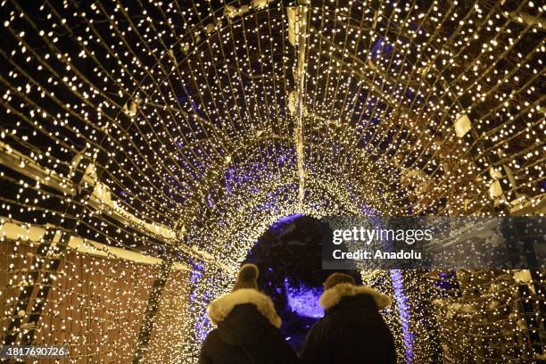 Visitors walk through a lights' corridor at the Winter Lights decoration tour during the traditional Christmas celebration at Skansen thematic park...
