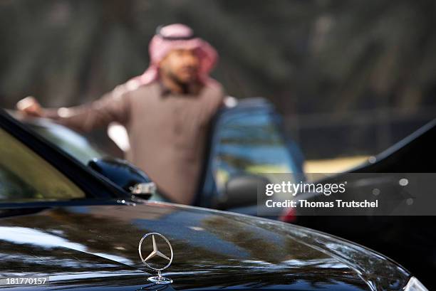 Sheik standing next to a Mercedes Benz.